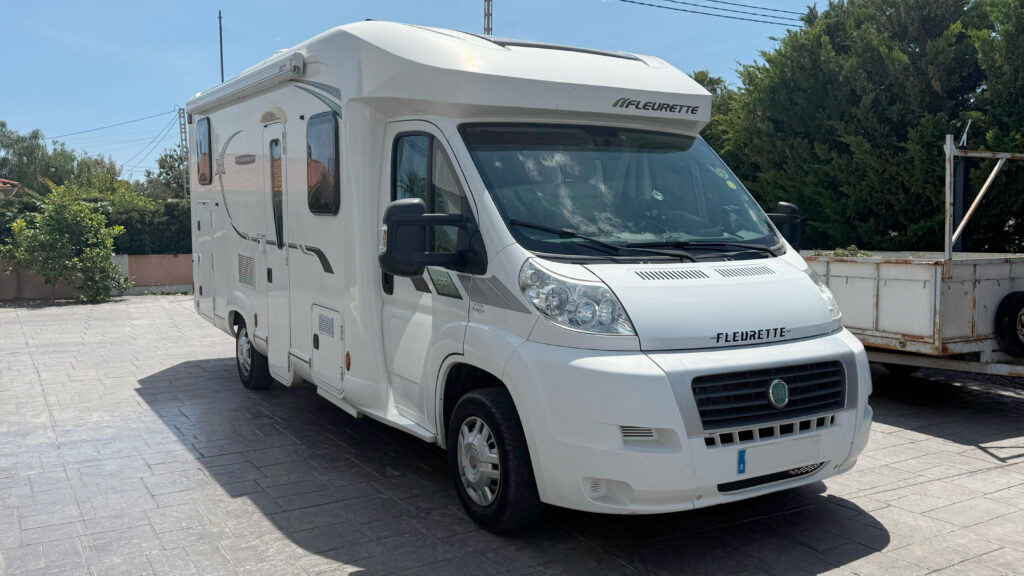 Autocaravana Fleurette blanca estacionada en exterior, vista frontal lateral, con diseño compacto y perfil aerodinámico.